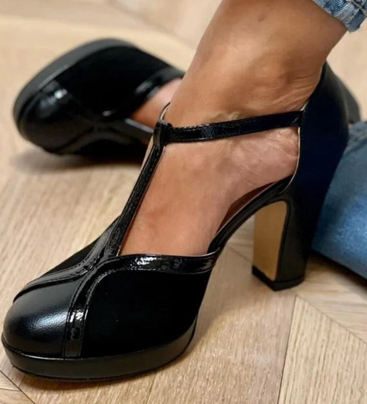 Black T-strap pumps with block heel, glossy finish, and adjustable silver buckle