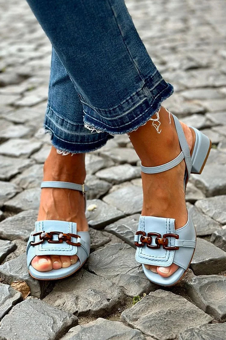 Light blue sandals with double buckle strap and low block heel on cobblestones