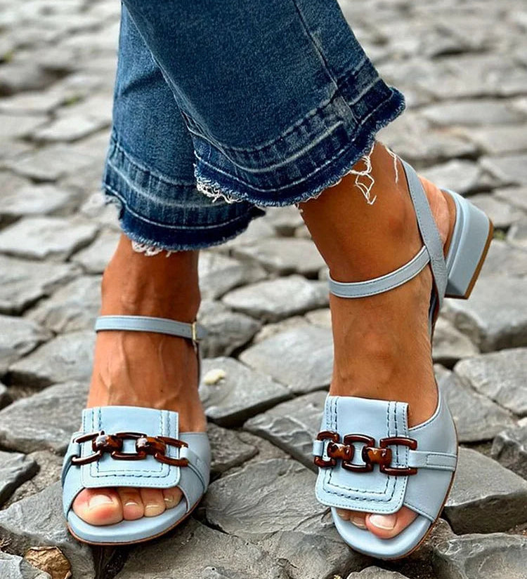 Light blue sandals with double buckle strap and low block heel on cobblestones