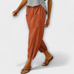 Rust orange harem pants with side pockets and button-tab cuffs, relaxed loose fit