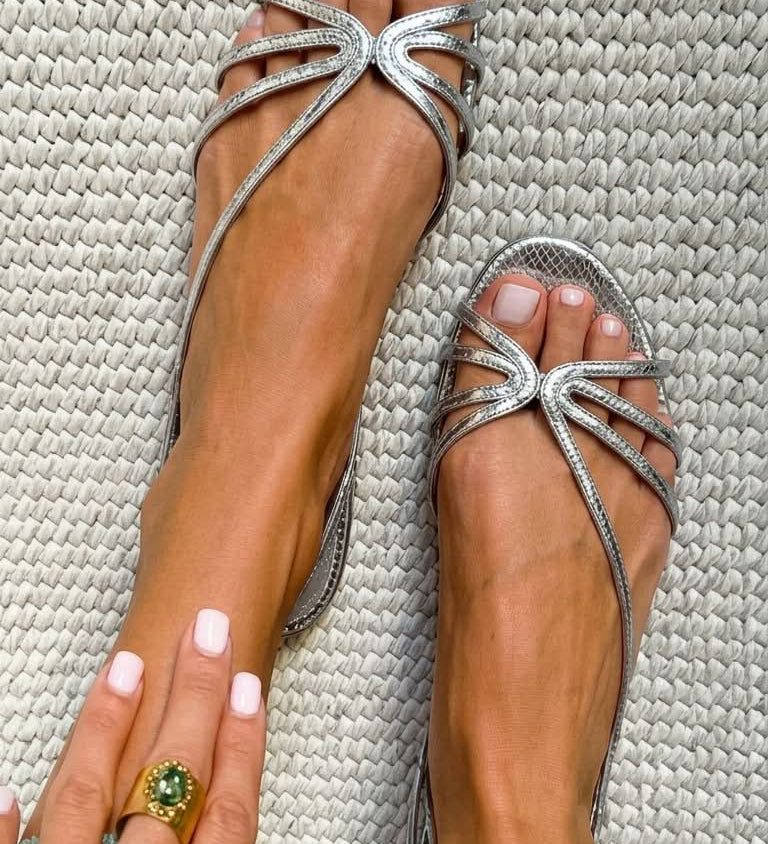 Metallic silver strappy flat sandals with bow-like accent at toe