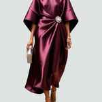 Burgundy satin long evening dress with draped batwing sleeves and jeweled waist brooch.