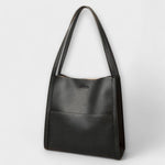 Natural leather tote bag, dark exterior, single top handles, small center clasp.