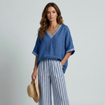 Women's blue V-neck top with contrast trim and striped wide-leg pants