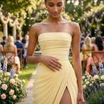 Strapless pale yellow corset maxi dress with gathered drape and front slit at event setting
