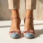 Pink leather heeled pumps with light-blue toe cap and ankle strap, bow detail