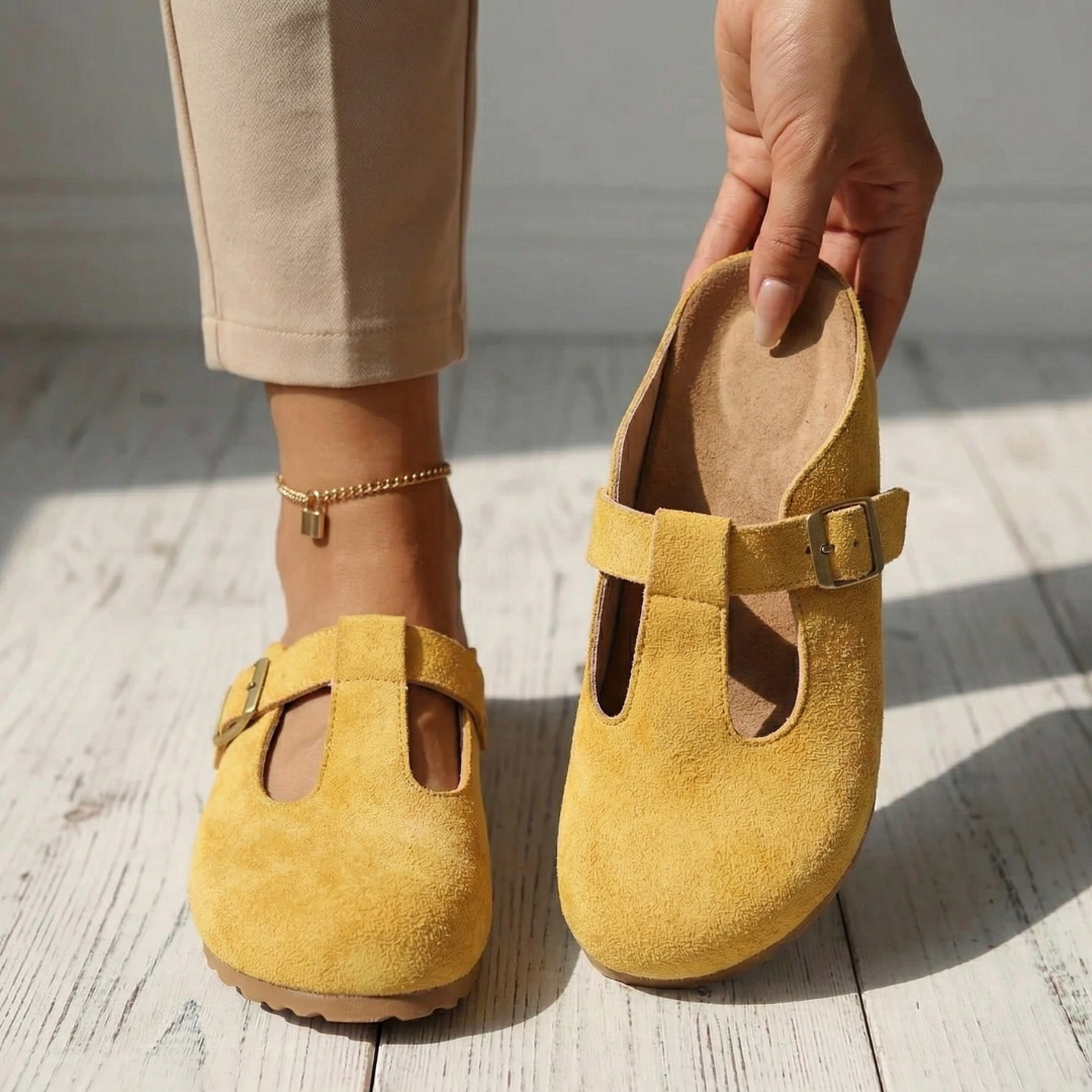 Yellow suede slide clogs with square buckle strap, side view and heel