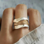 Silver ring with gold-thread stripes and smooth wave band, on finger close-up