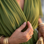 Green wrap dress fabric close-up with gathered folds and soft drape