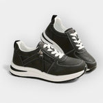 Anatomical black sneakers with white laces, side zipper, and cushioned white sole.