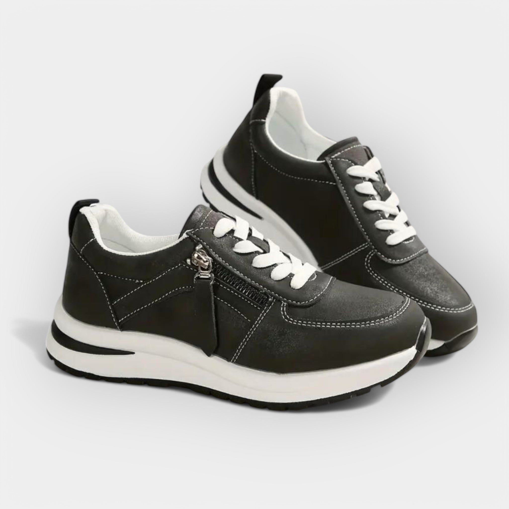 Anatomical black sneakers with white laces, side zipper, and cushioned white sole.