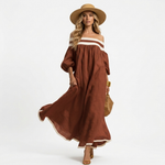 Rust brown long off-shoulder maxi dress with white stripe at neckline and wide sleeves.