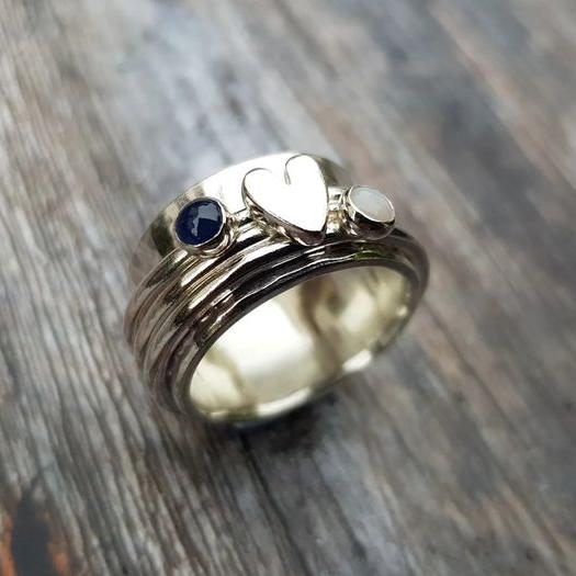 Silver heart ring with blue and white gemstones on a band