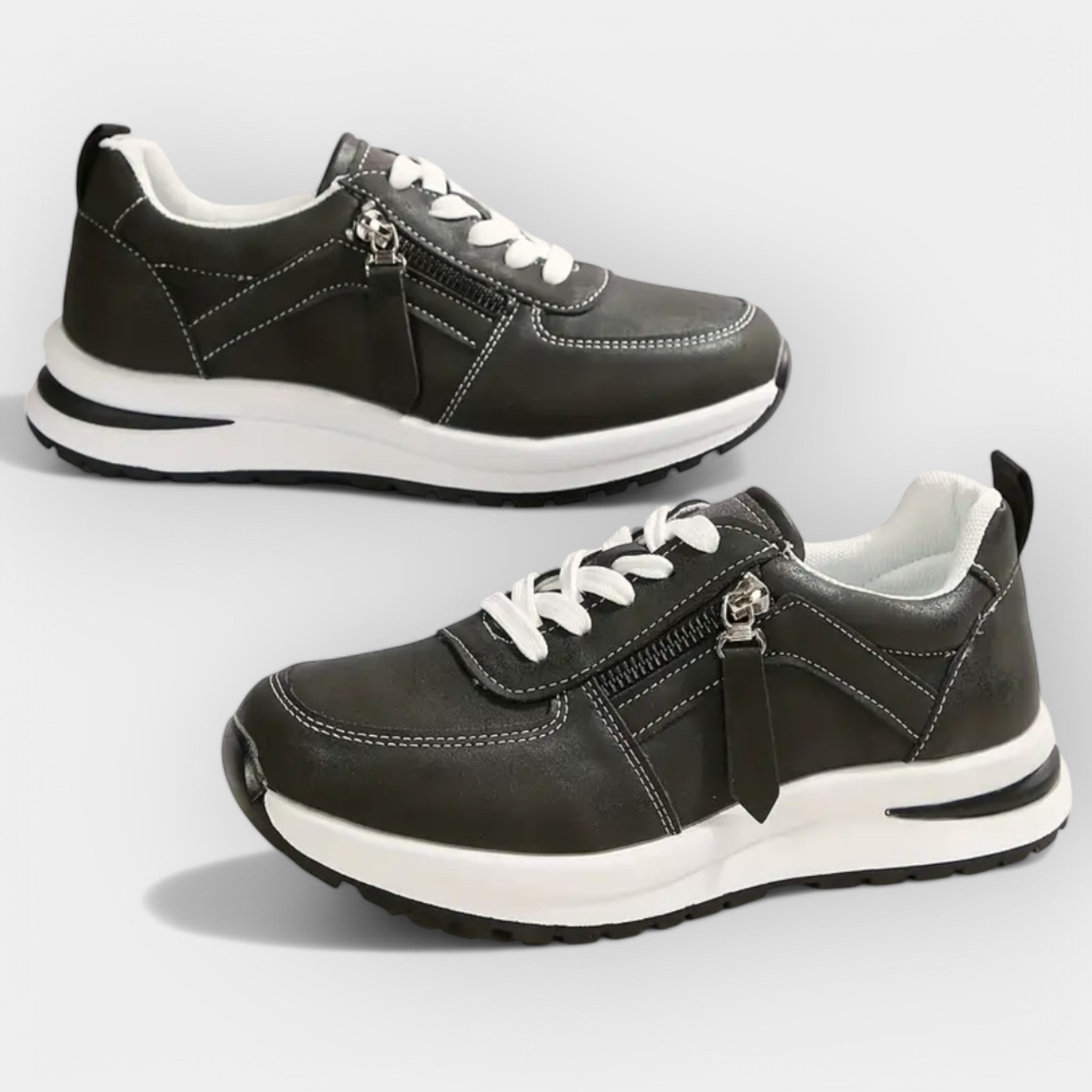 Anatomical black sneakers with white laces, side zipper, and white rubber sole.