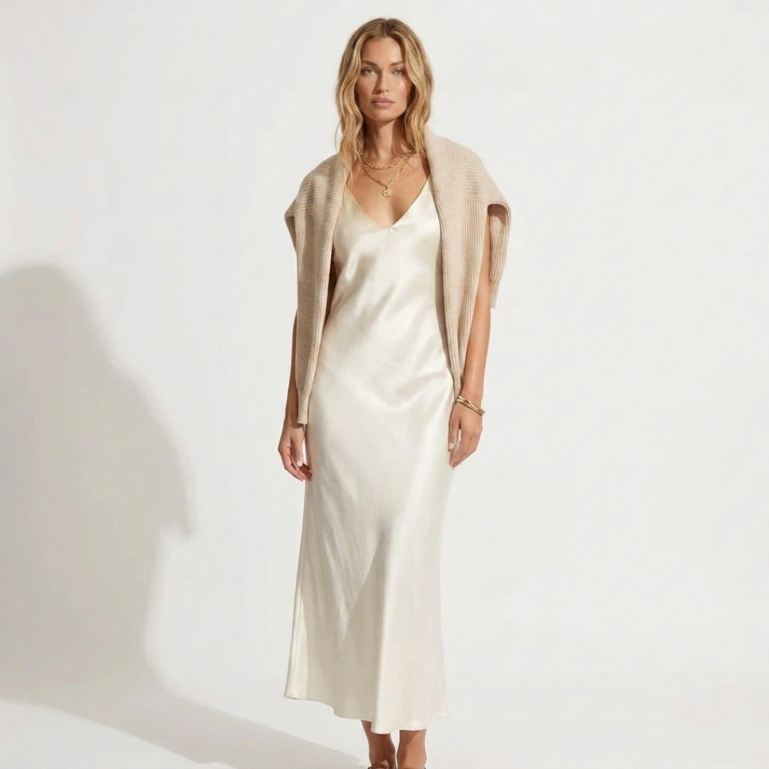 Madalina knit V-neck sweater over white satin midi dress, angled front view