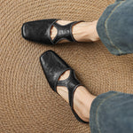Black natural leather mule flats, close-up side view with low block heel and cutouts