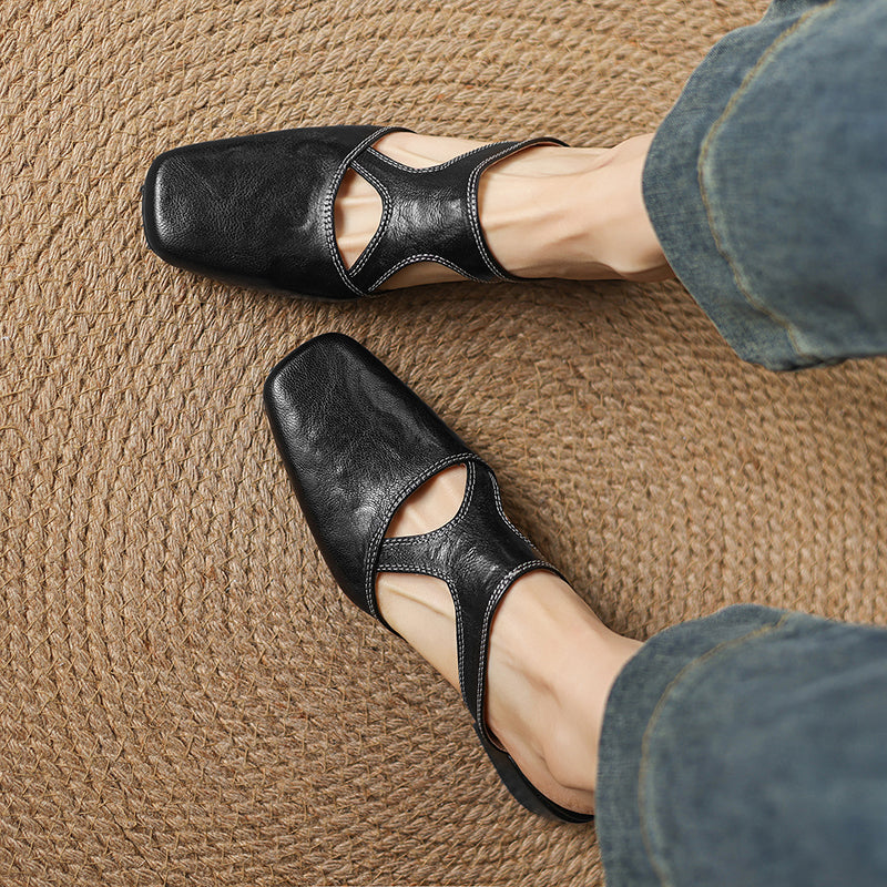 Black natural leather mule flats, close-up side view with low block heel and cutouts