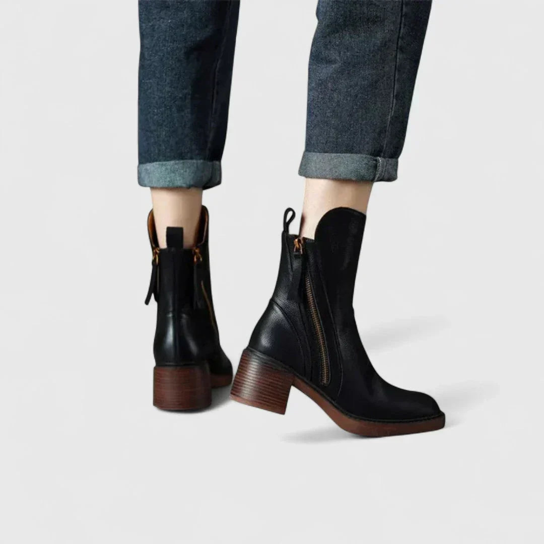 Pair of black ankle boots with side zipper and block heel on denim