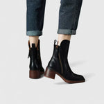 Pair of black ankle boots with side zipper and block heel on denim