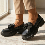 Water-resistant loafers in black with bow, glossy finish, and chunky tread sole