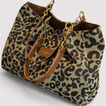 Leopard print tote bag with brown strap, gold chain handles, and front patch pocket