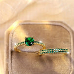 Gold-tone ring with oval emerald green gemstone and slim green pave band