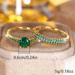 Gold-tone duo rings with oval green center stone and curved green pave detail