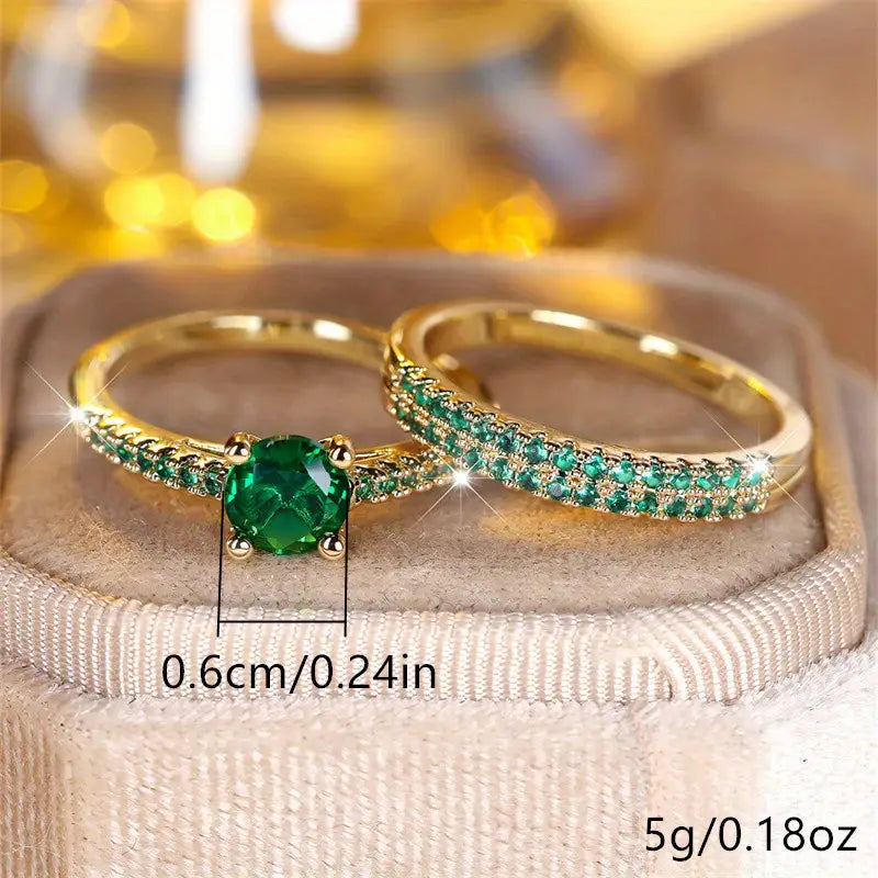 Gold-tone duo rings with oval green center stone and curved green pave detail