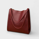 Burgundy natural leather tote bag with curved strap handles and front seam panel