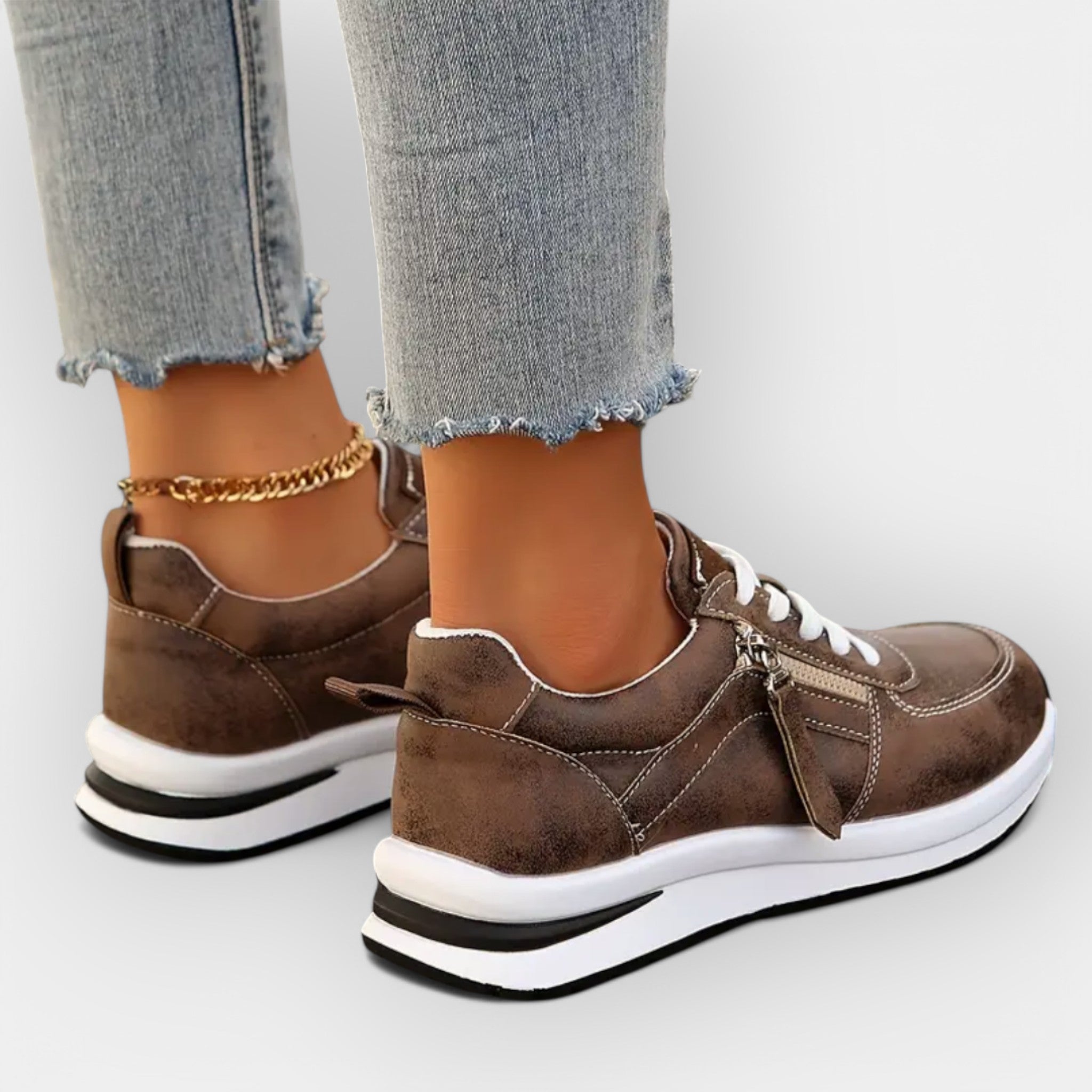 Anatomical brown sneakers with white laces, side zipper, and white tread sole.