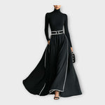 Black long-sleeve maxi dress with high neck, silver-buckle waist belt, flowing skirt