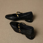 Black leather ballet flats pair with gold buckle strap, side view