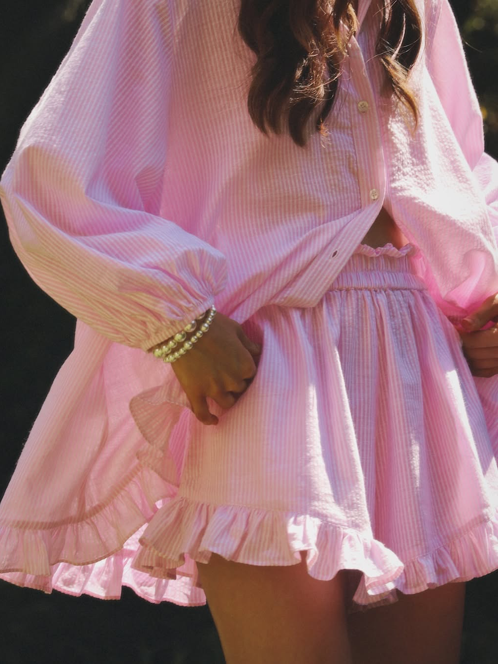 Close-up of pink button-up mini dress set with gathered waist and ruffled tiers
