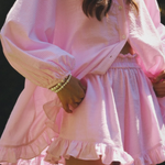 Close-up of pink button-up mini dress set with gathered waist and ruffled tiers