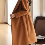 Tan winter coat with notch lapels, waist belt, and long sleeves