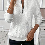 White cable-knit zip-front sweater with long sleeves and textured braided pattern.