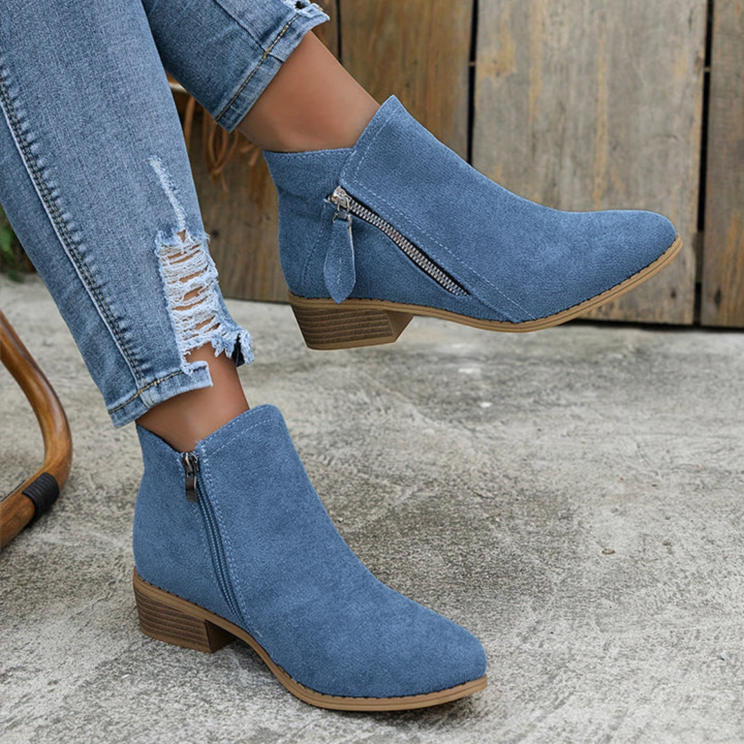 Blue suede ankle boots with side zipper, low block heel, worn with jeans.
