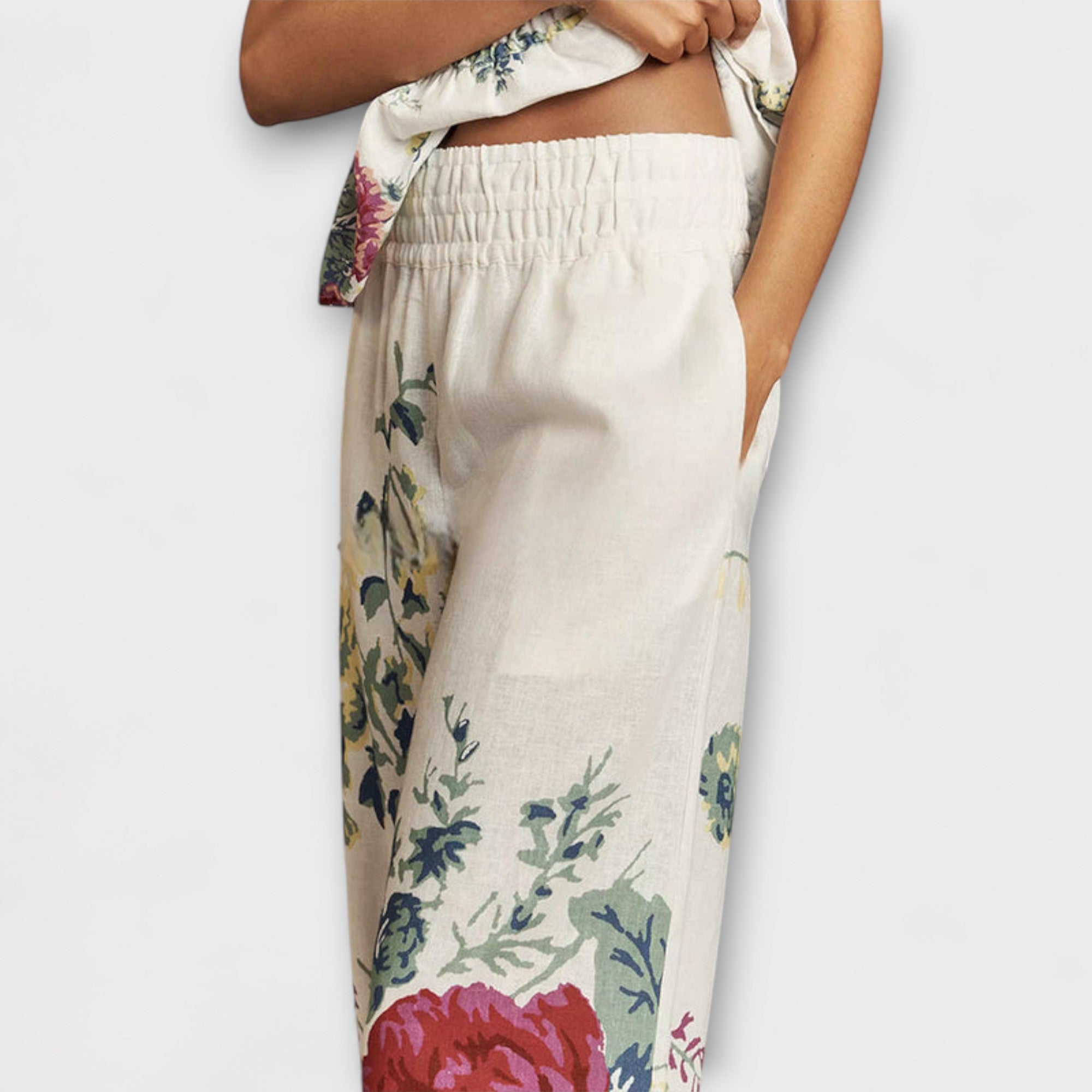Elastic-waist wide-leg trousers in cream with floral print, side view and curved hem detail