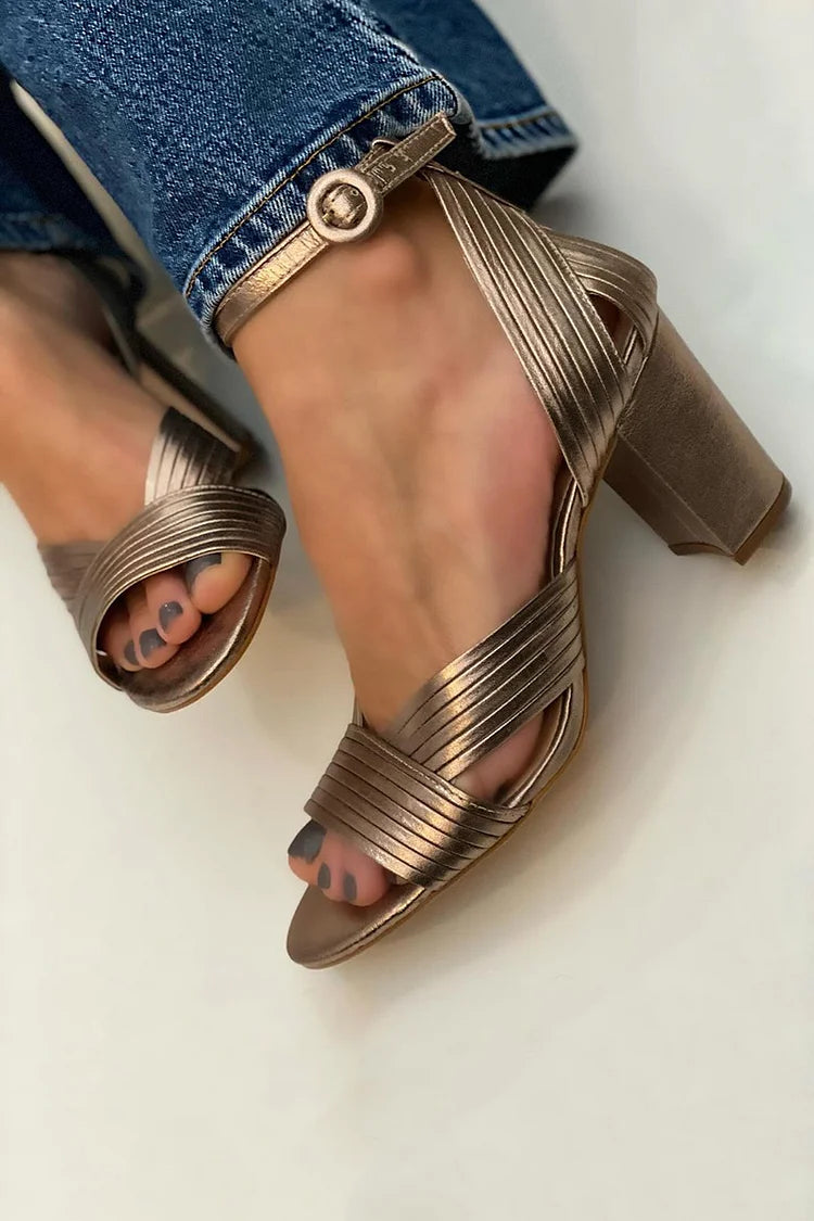 Metallic bronze heeled sandals with crisscross straps and buckle ankle strap.