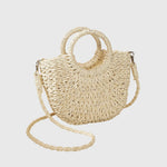 Light beige woven straw shoulder bag with ring handles and long braided crossbody strap.