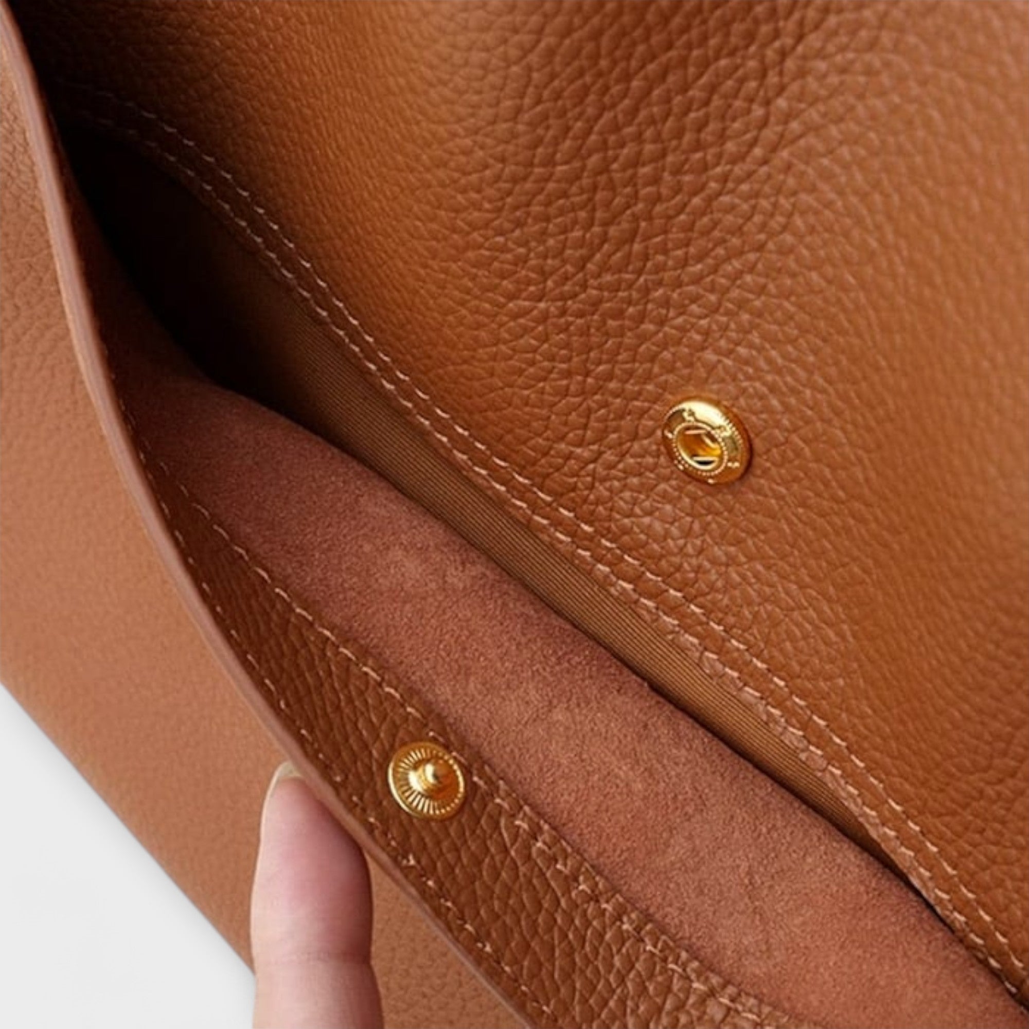 Natural leather bag interior with gold snap hardware and stitched seam detail