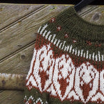 Olive green knit sweater close-up with white and red geometric diamond pattern