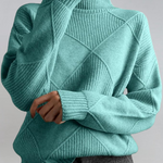 Teal green high-neck sweater with ribbed turtleneck and diagonal knit panel detail.
