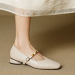 Cream leather ballet flats with rounded toe, low block heel, and gold buckle strap