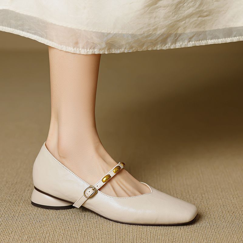 Cream leather ballet flats with rounded toe, low block heel, and gold buckle strap
