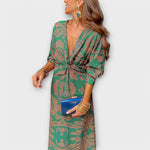 Elegant long-sleeve V-neck dress with green and gold ornate print, knotted waist tie