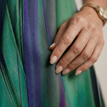 Close-up of green and purple vertical-striped fabric with soft sheen, hand on dress