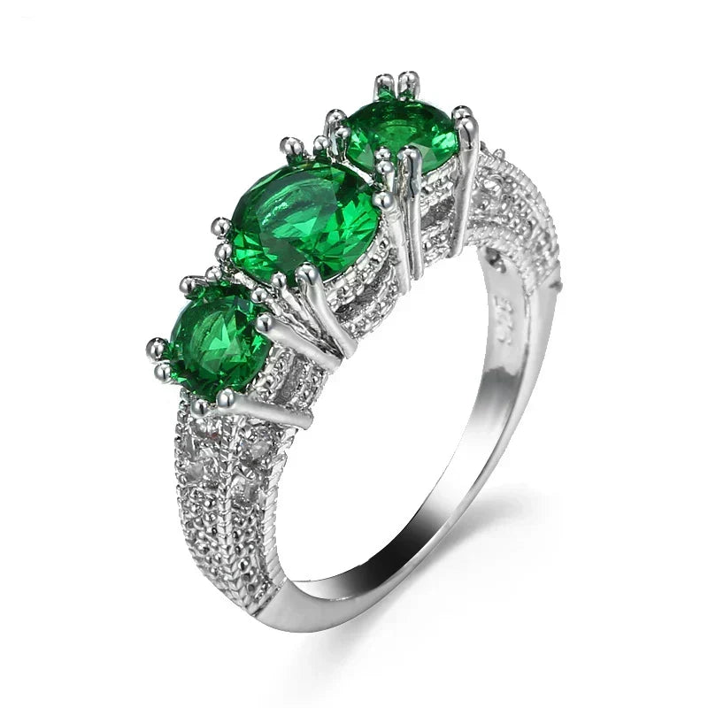 Sparkling emerald-stone ring with three green stones and silver halo accents