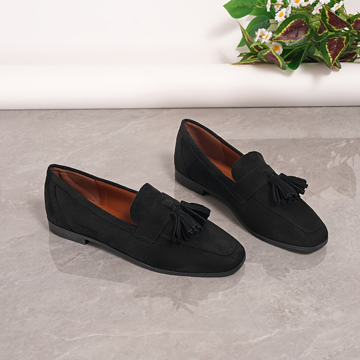 Black suede tassel loafers with slip-on style and low block sole