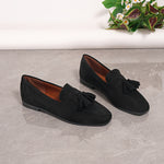 Black suede tassel loafers with slip-on style and low block sole